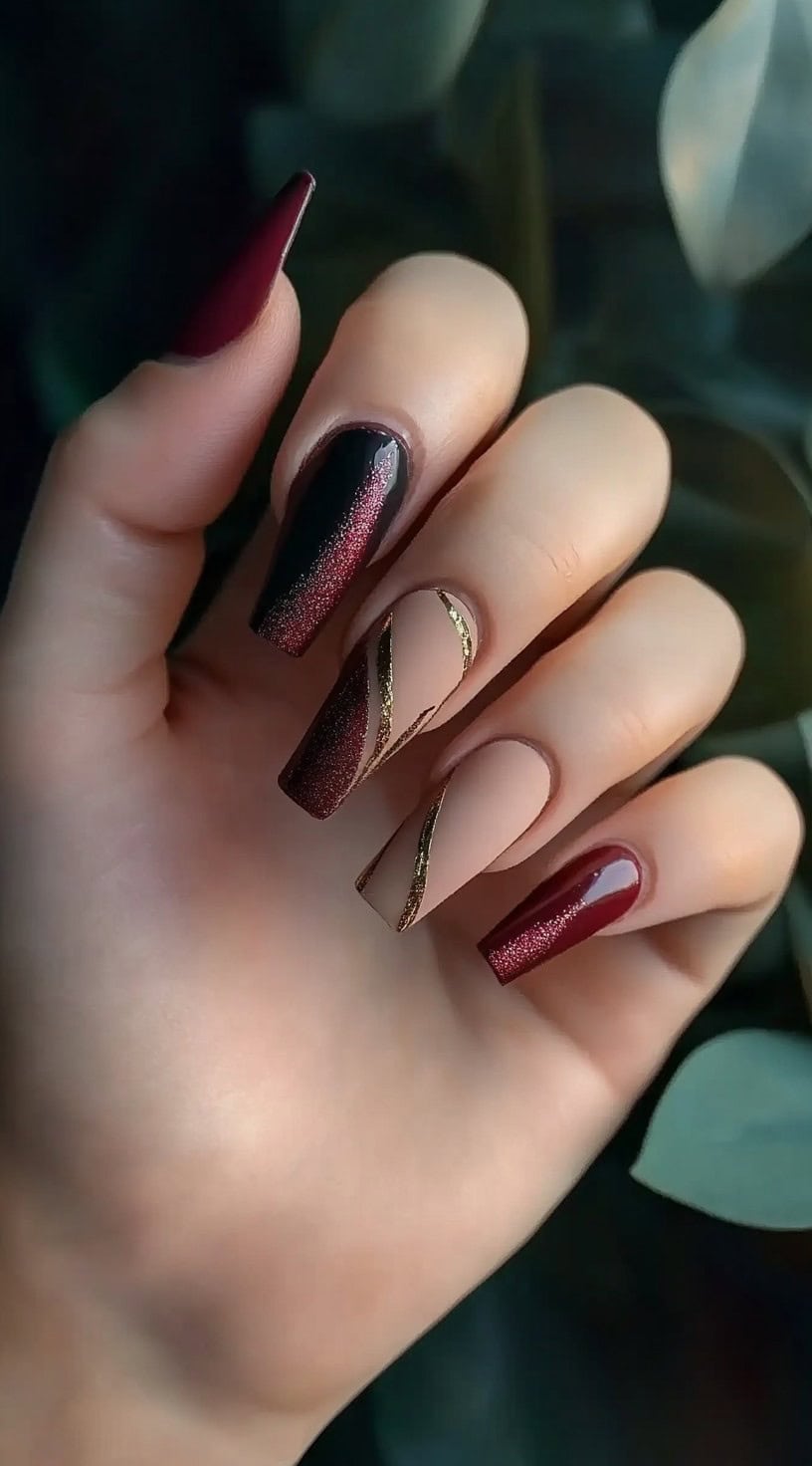Long coffin-shaped nails featuring a mix of burgundy, nude, and gold-accented designs for a modern touch.