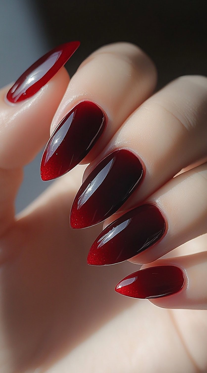 Glossy, stiletto-shaped nails with a translucent burgundy jelly effect and a high-shine finish.