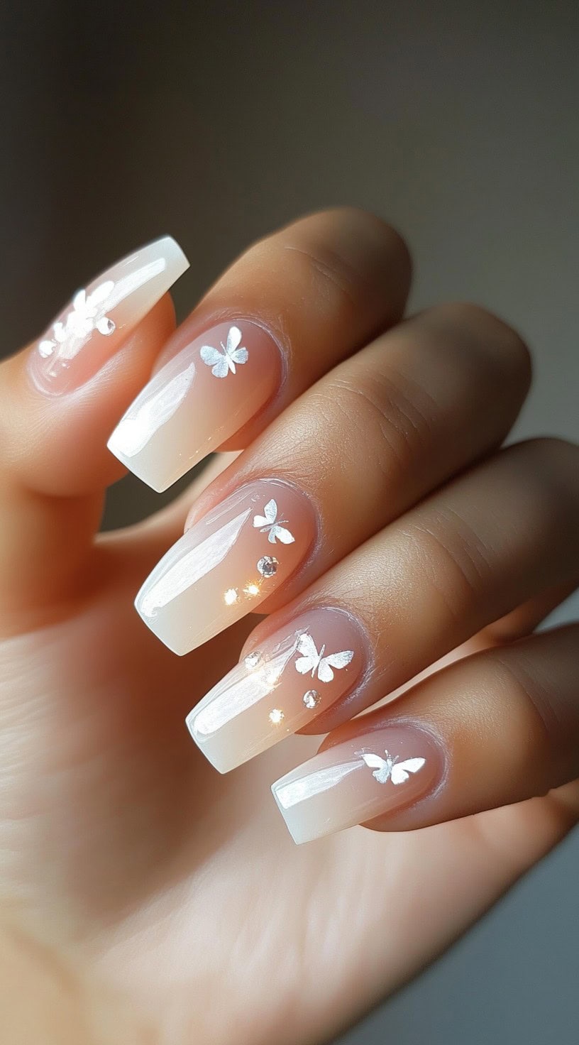 Coffin-shaped nails with a white ombre base and butterfly decals.