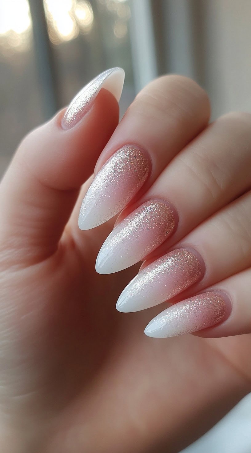 Almond-shaped nails with glitter ombre from nude to white tips.