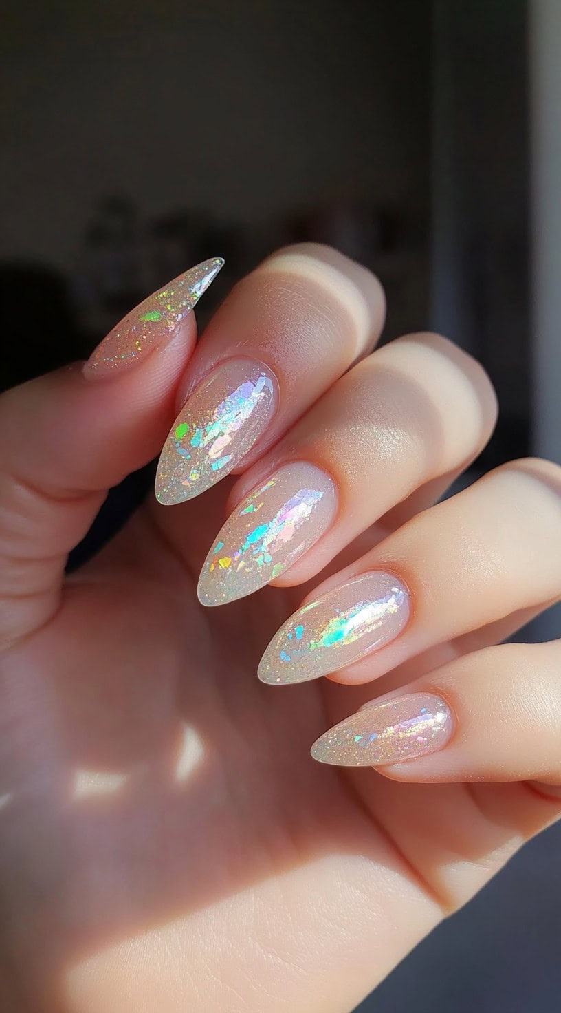 Almond-shaped nails with a translucent base featuring iridescent chrome flakes reflecting pastel hues.