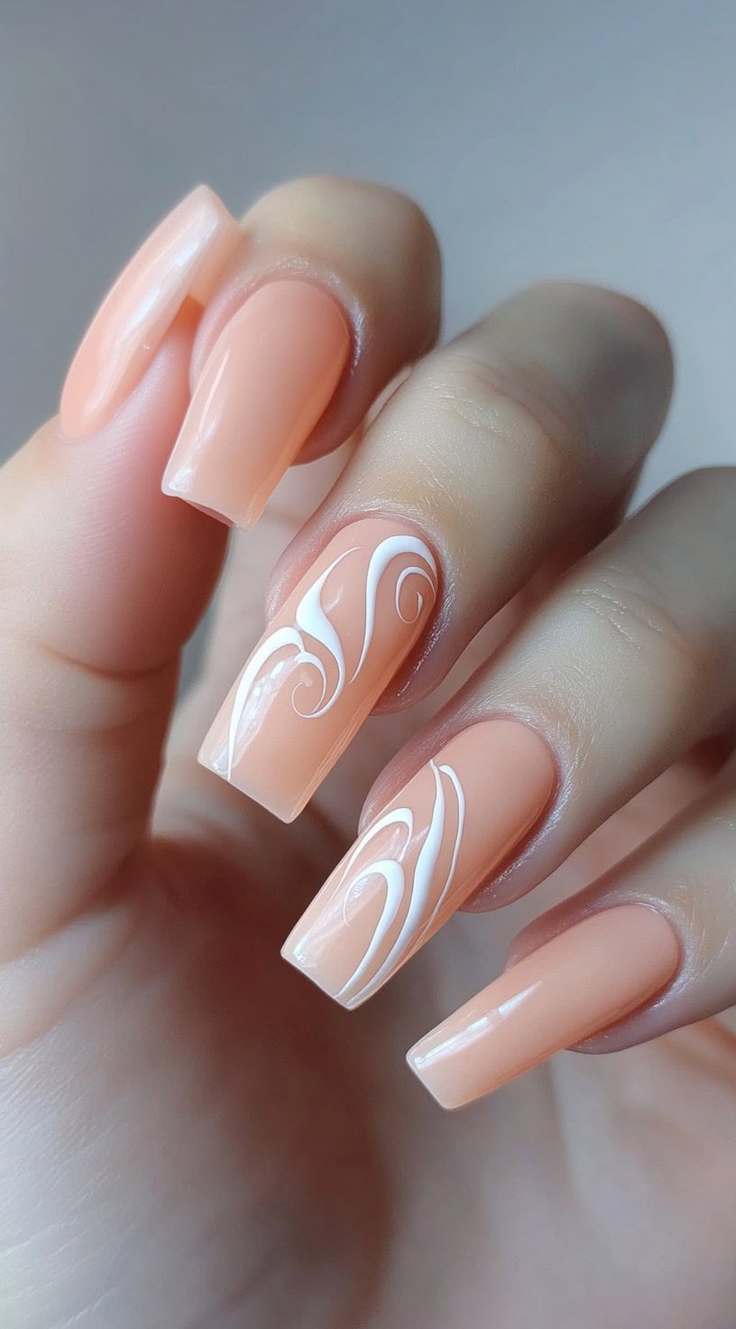Long coffin nails with a peach base and white swirl accents.