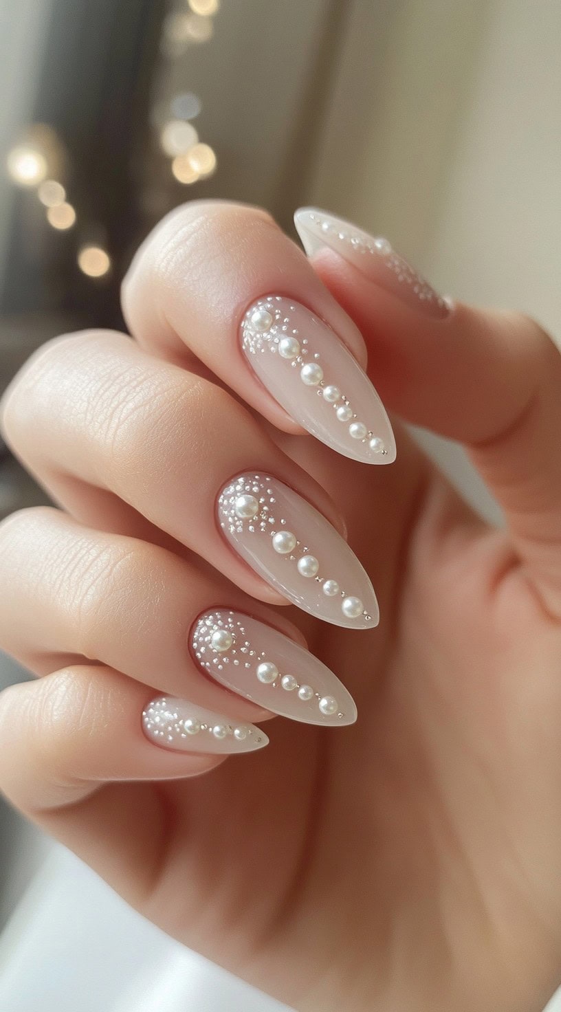 Glossy almond-shaped nails with delicate pearl accents arranged in a vertical line.