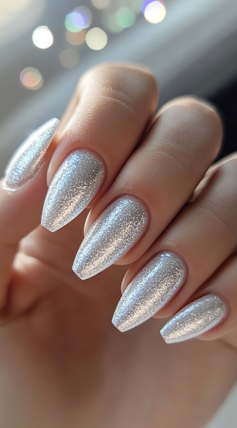 A set of ultra-glossy platinum chrome stiletto nails with a high-shine metallic finish.