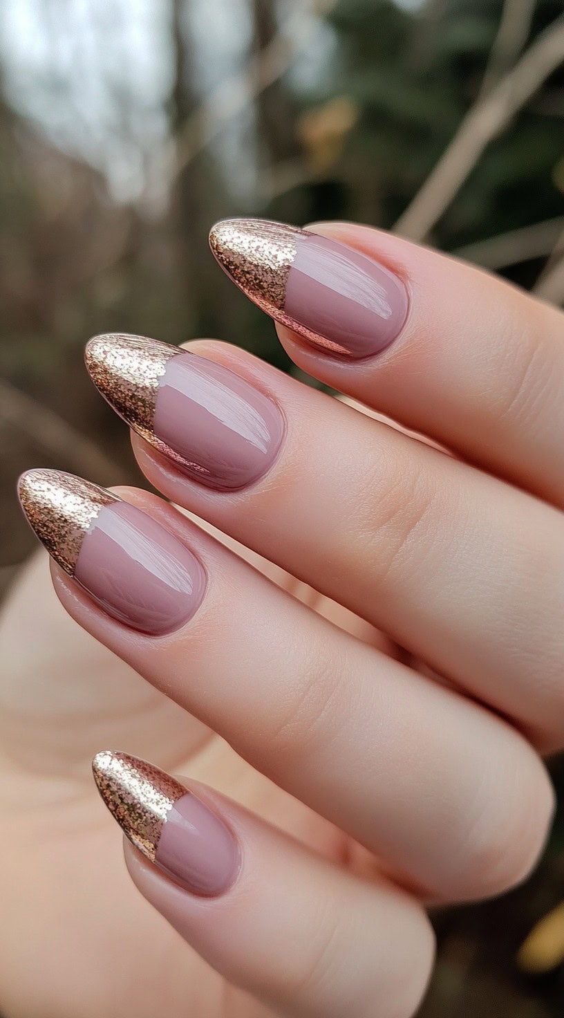 Almond-shaped nails with a sheer mauve base and glittering rose gold French tips.