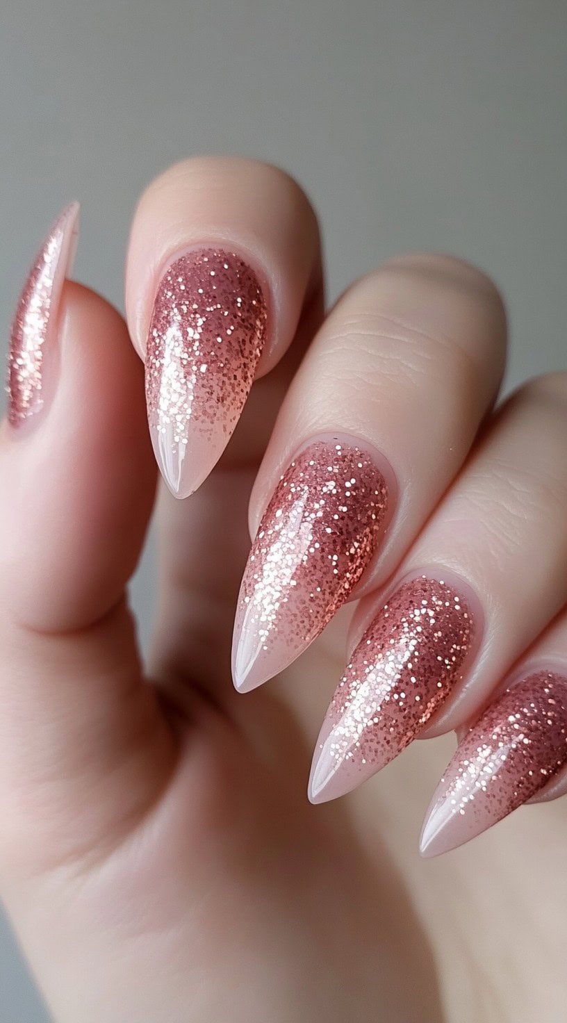 Stiletto-shaped nails with a rose gold glitter ombre design.