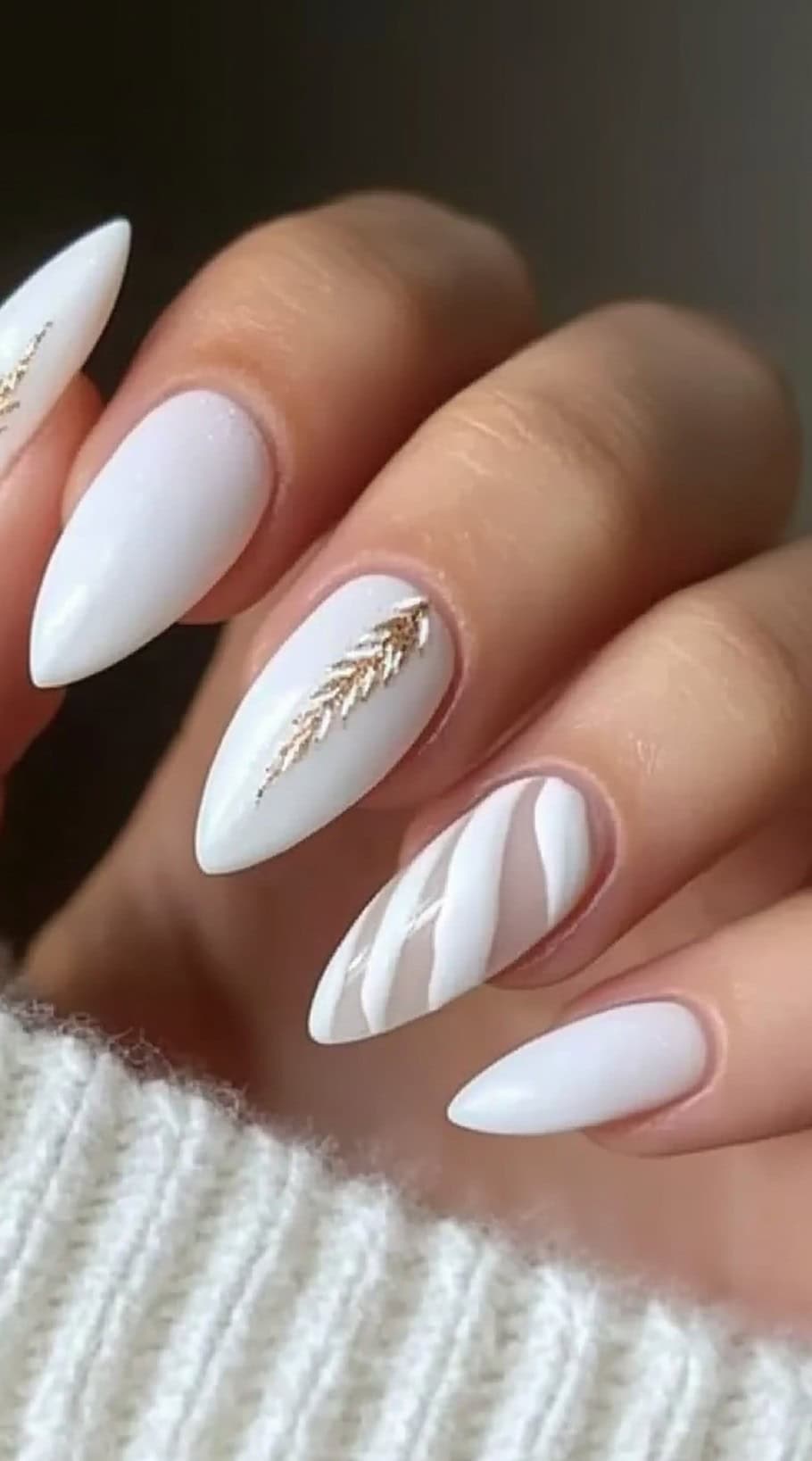 Almond-shaped white nails with gold leaf accents and a glossy finish.