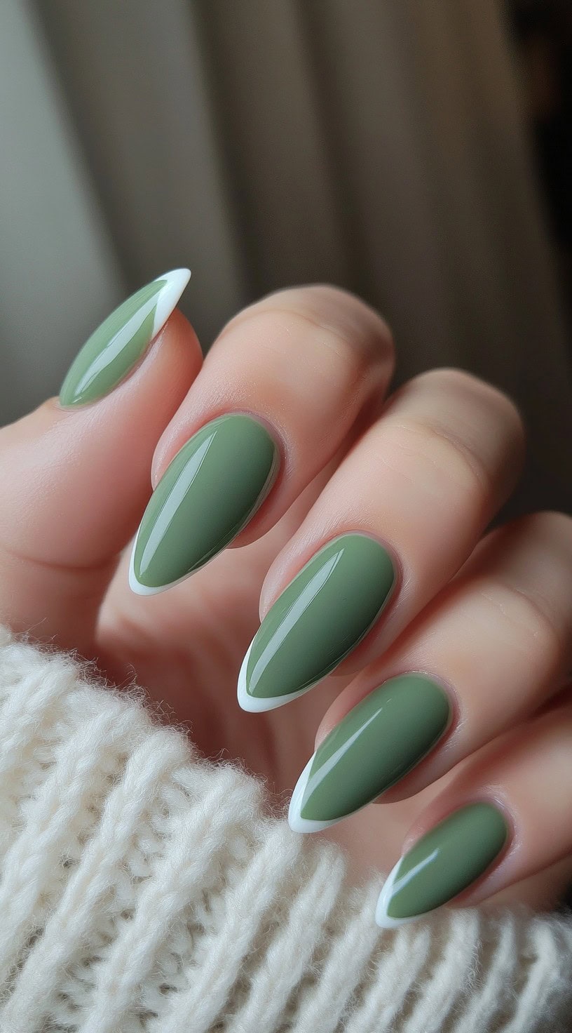 A hand with almond-shaped nails painted in a glossy matcha green, each tipped with a crisp white French edge.