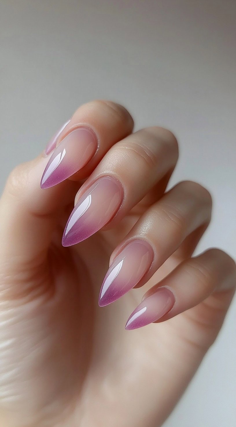 Almond-shaped nails featuring a sheer nude base blending into a muted purple-pink ombre tip.