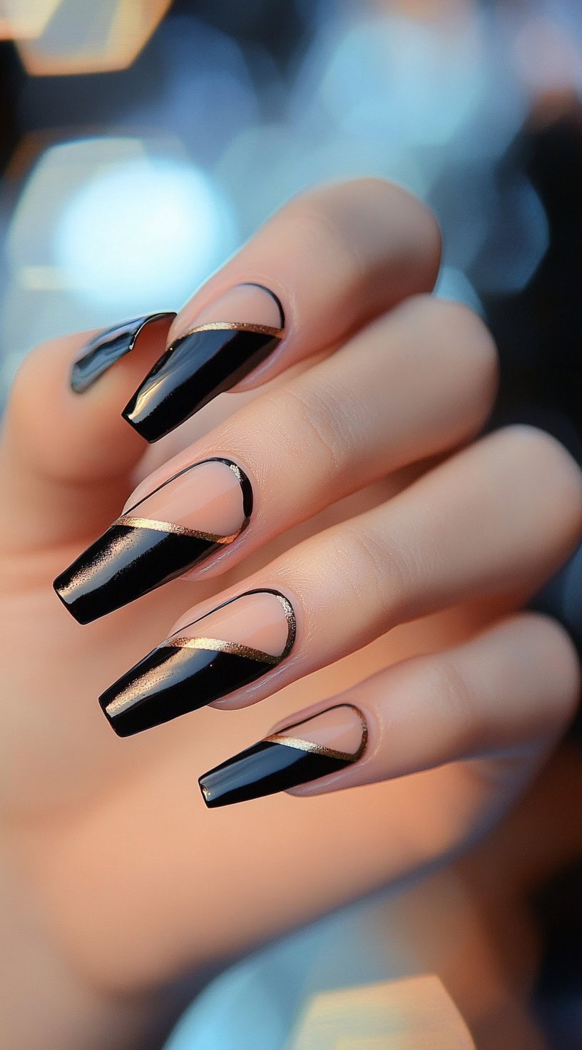 A set of long coffin-shaped nails with a sheer nude base and bold black sections, accented with metallic gold lines for a geometric effect.