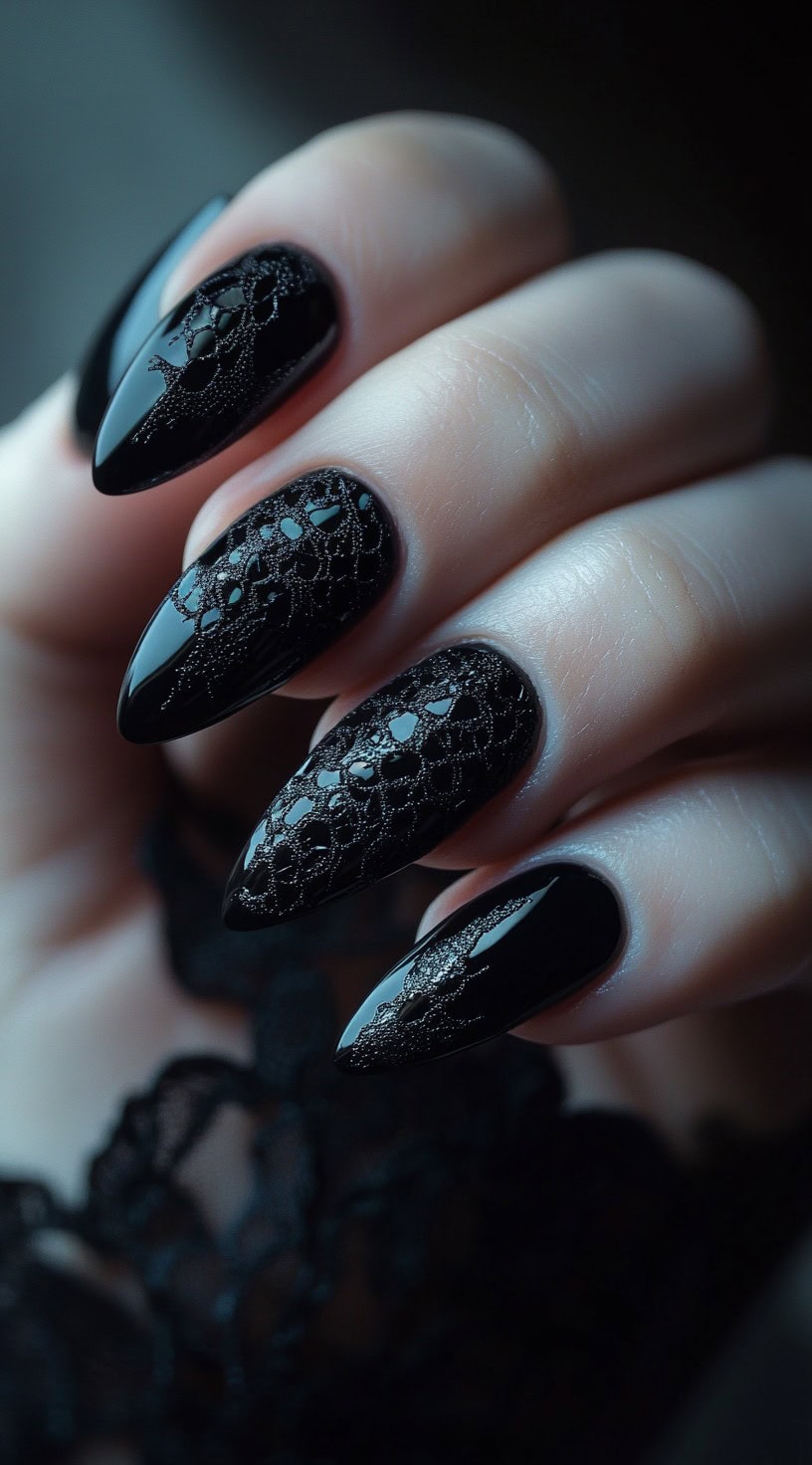 A set of stiletto-shaped nails with a glossy black base, featuring a textured lace-like pattern for a luxurious, dimensional effect.