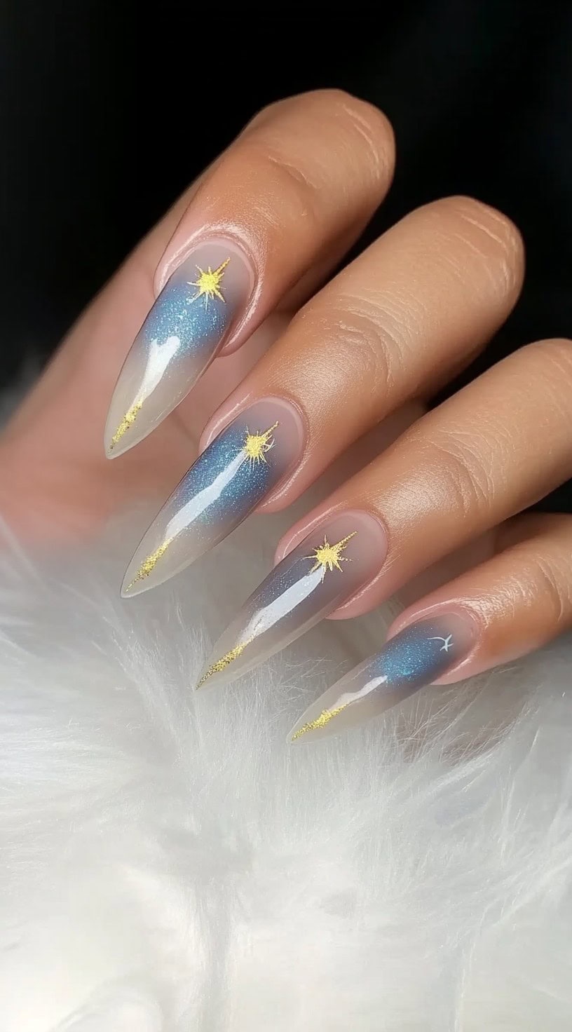 Long, tapered nails with a translucent nude-to-blue aura fade, featuring delicate golden shooting star accents.