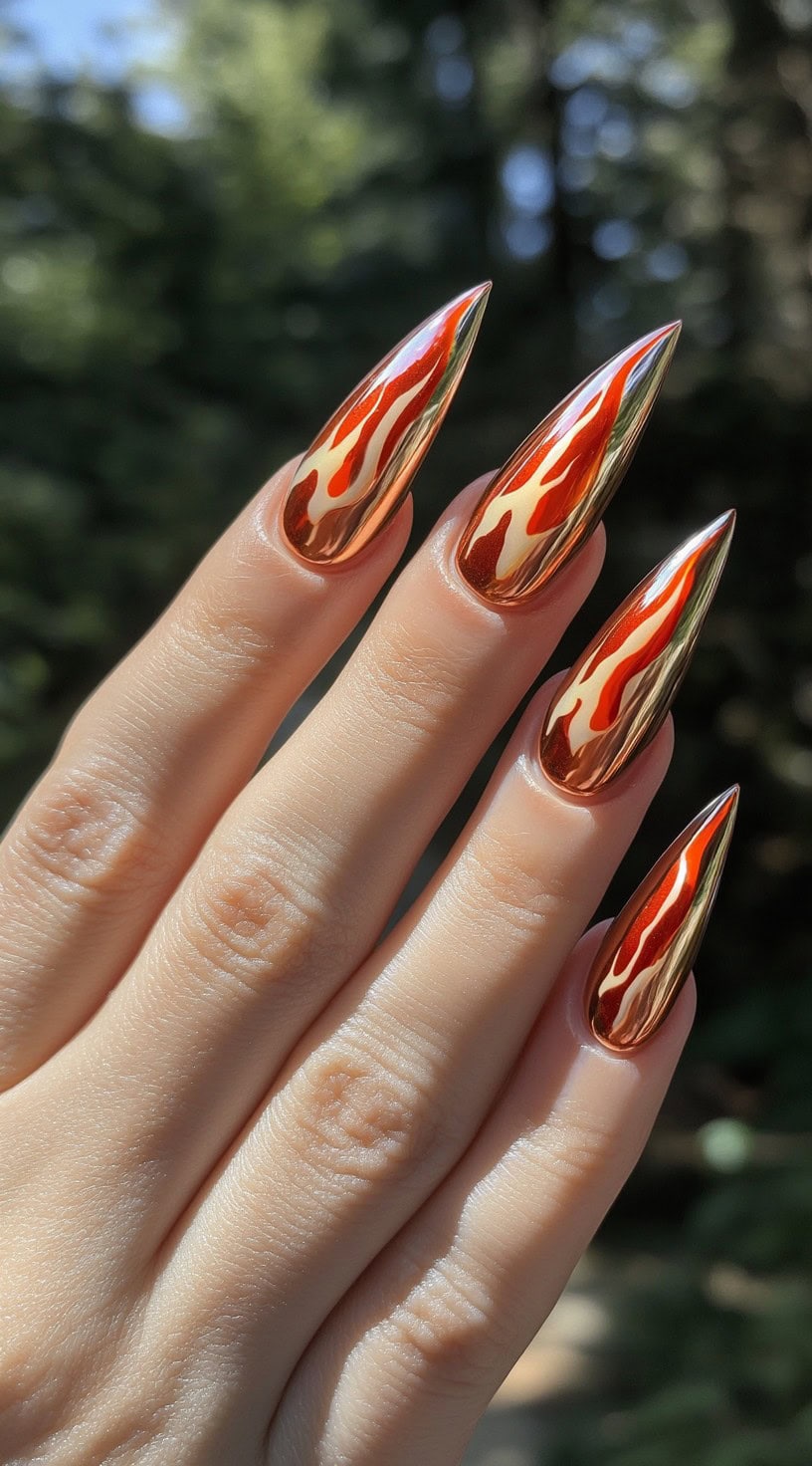Hand with ultra-pointed stiletto nails in reflective chrome red and copper flame design.