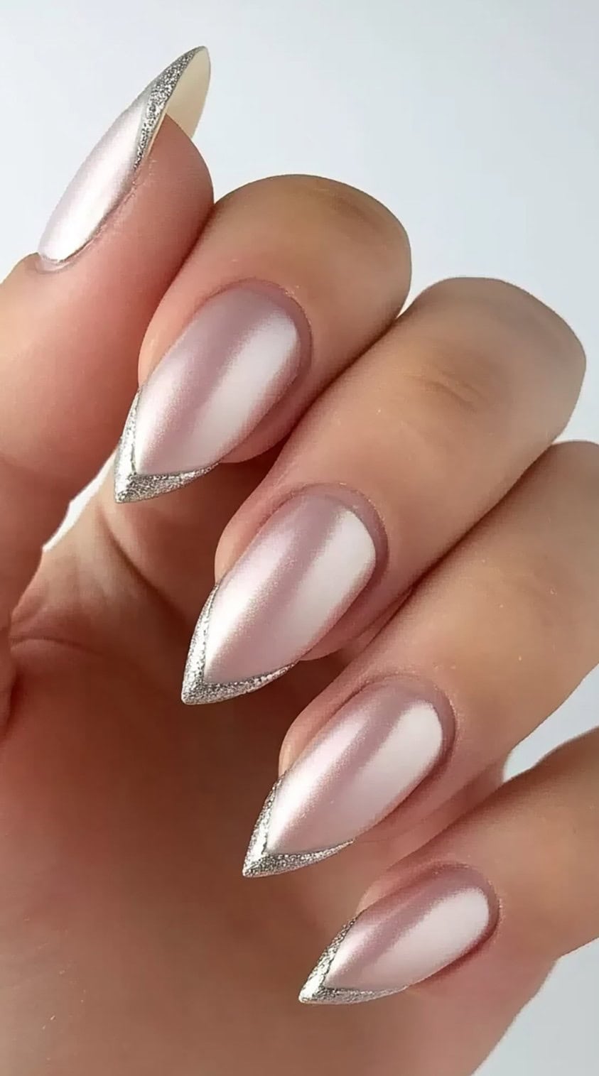 Stiletto-shaped nails with a pearlescent pink chrome base and thin silver glitter French tips.