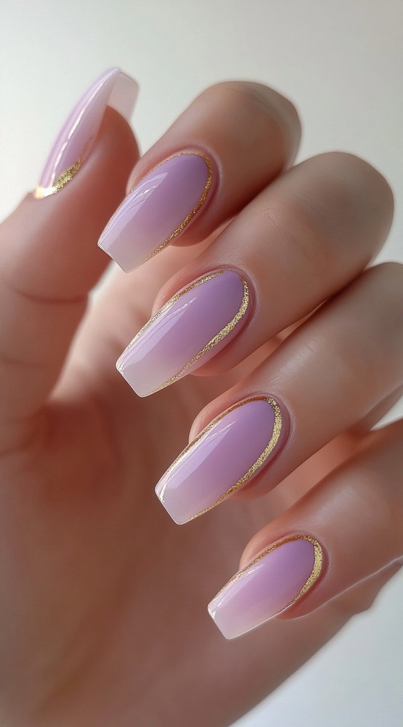 Coffin-shaped nails with a soft lavender-pink ombre and thin gold foil detailing tracing the nail contour.