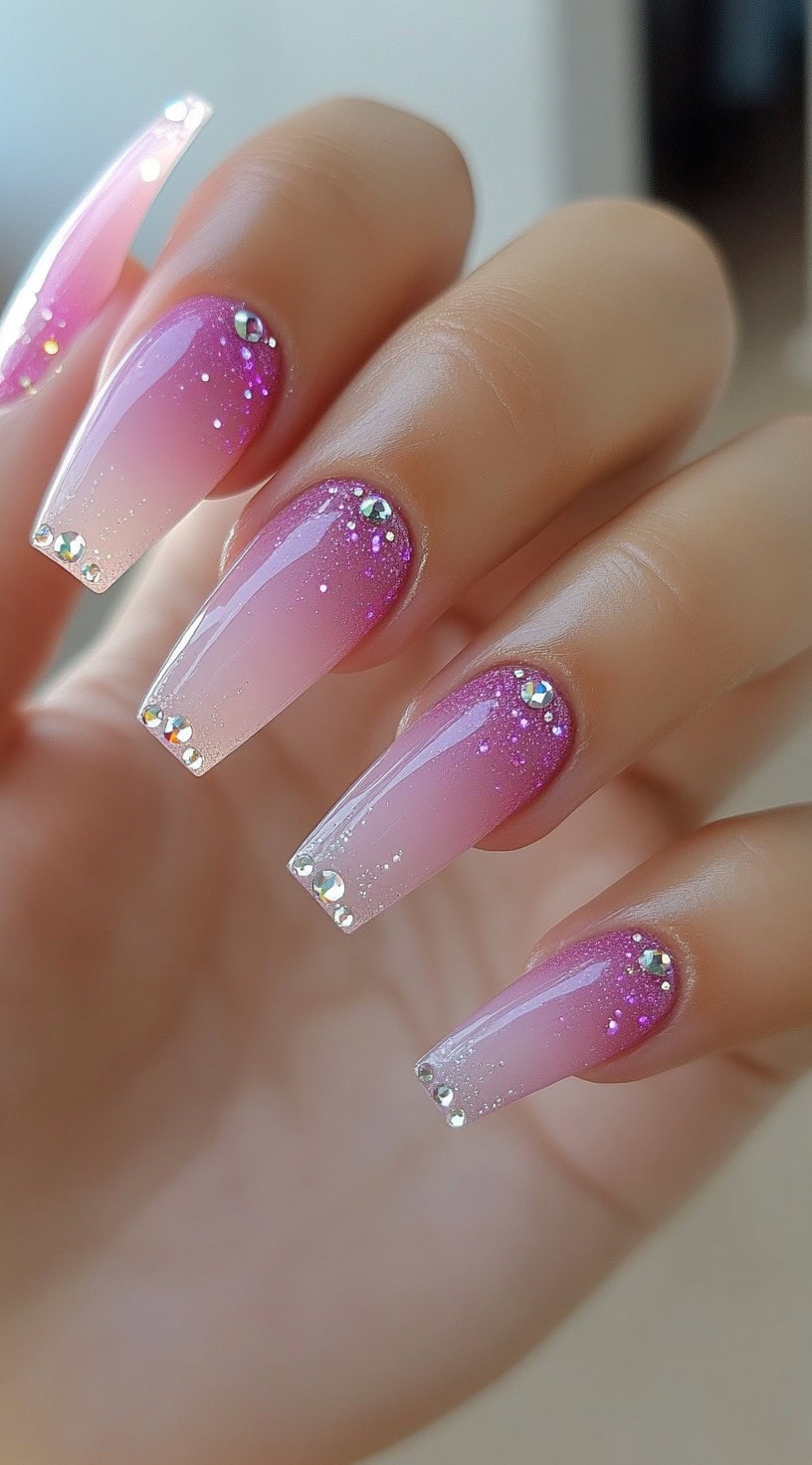 Coffin-shaped nails blending pink and purple tones, finished with glitter and a line of rhinestones at the cuticle and tip.