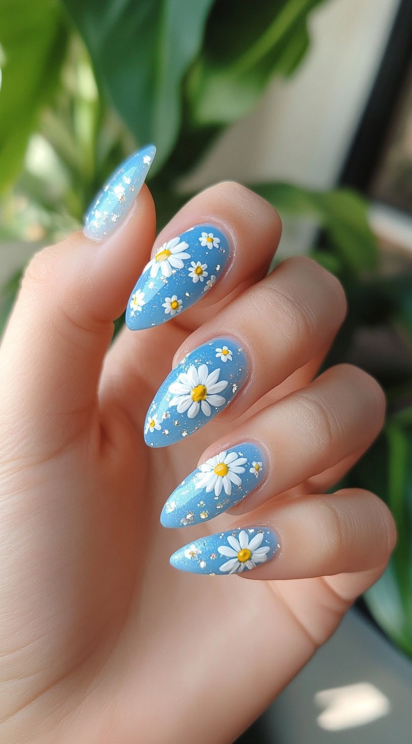 Stiletto-shaped nails with a sky-blue base and delicate white daisy floral accents.