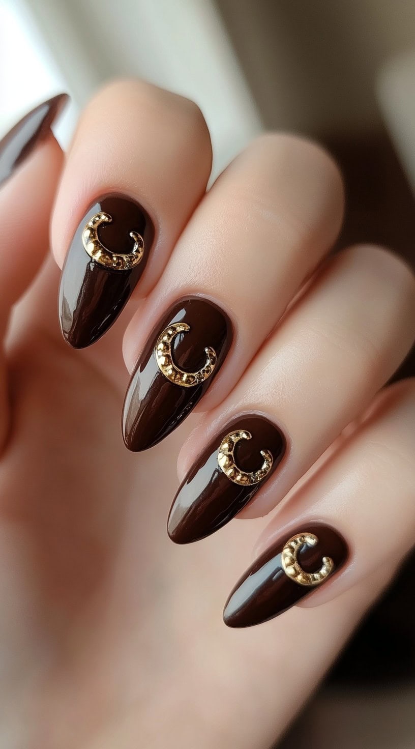 Glossy deep brown almond nails with gold 3D horseshoe embellishments on select nails.