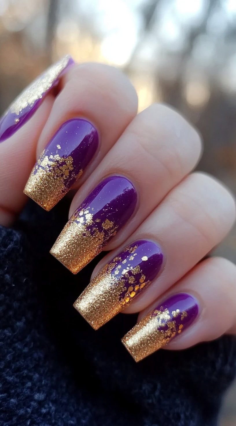 Close-up of long square nails painted in a glossy purple base with gold glitter gradient tips.
