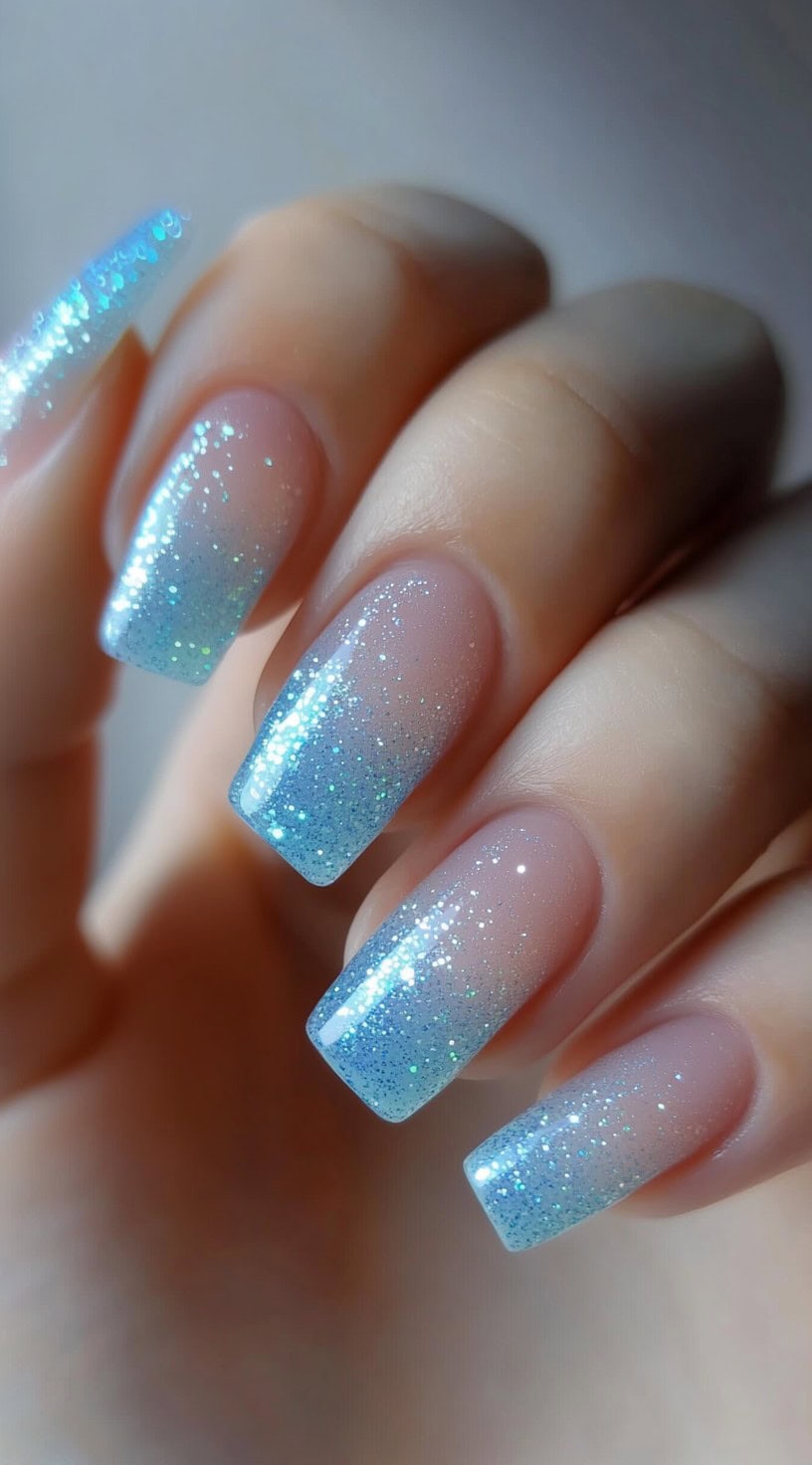 Coffin-shaped nails with a clear-to-blue glitter ombre effect.