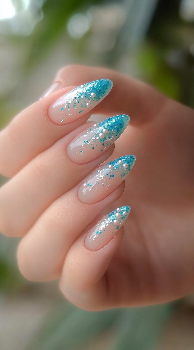 Almond-shaped nails with a light blue glitter ombre design and pearl accents.