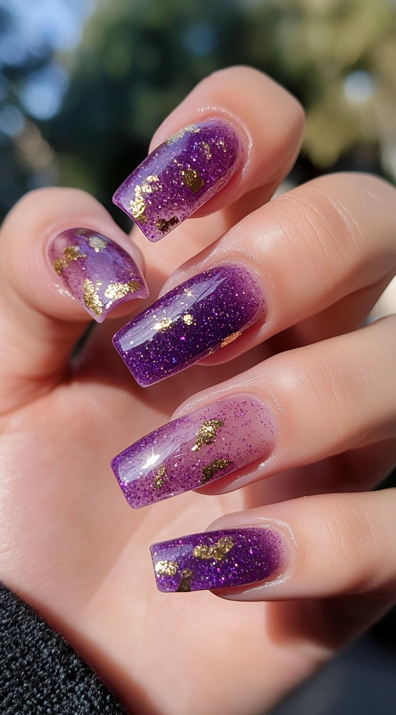 Coffin-shaped nails layered with translucent purple glitter polish and chunks of gold foil throughout.