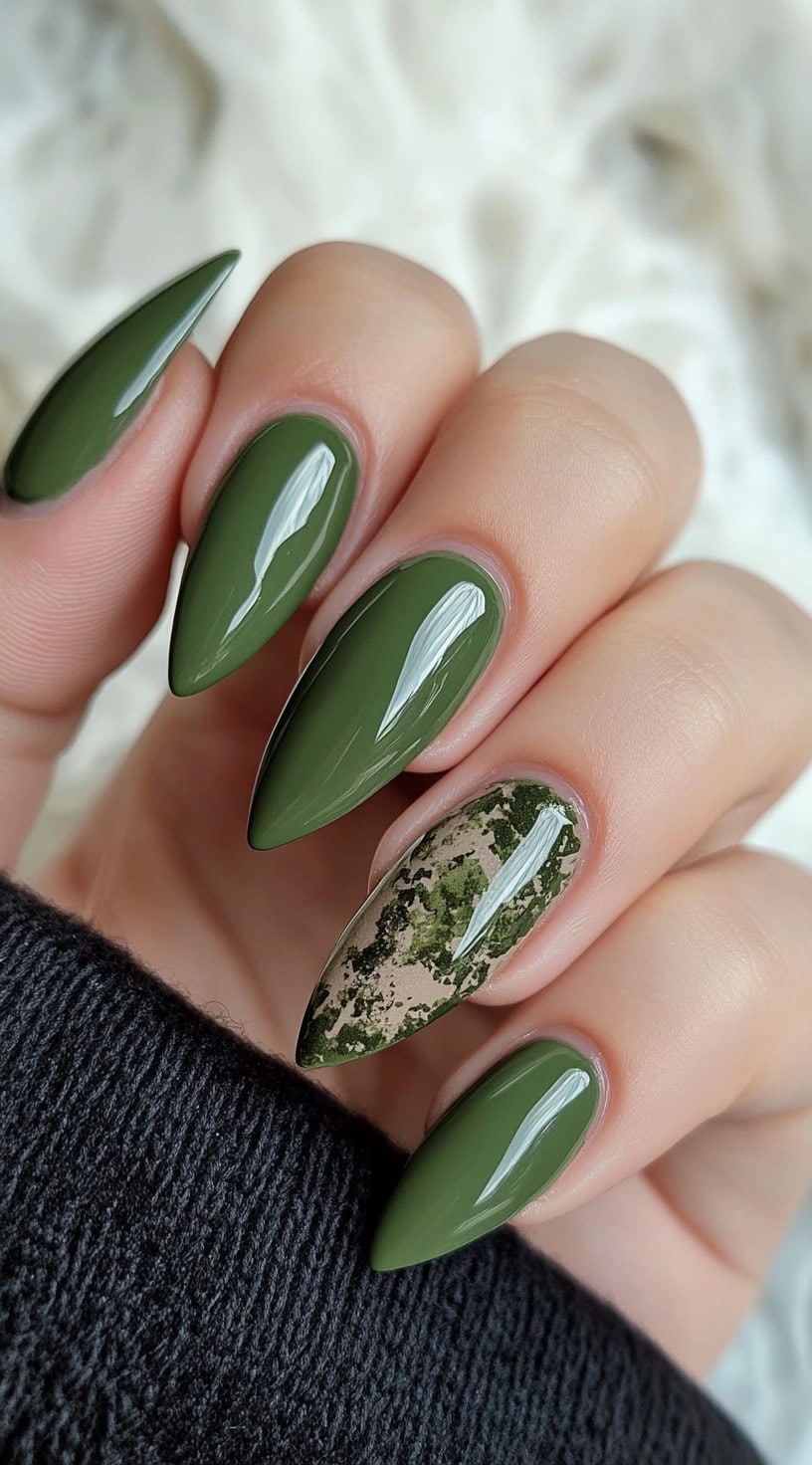 Almond-shaped nails in glossy matcha green with a single nude accent nail featuring moss-like green marble art.