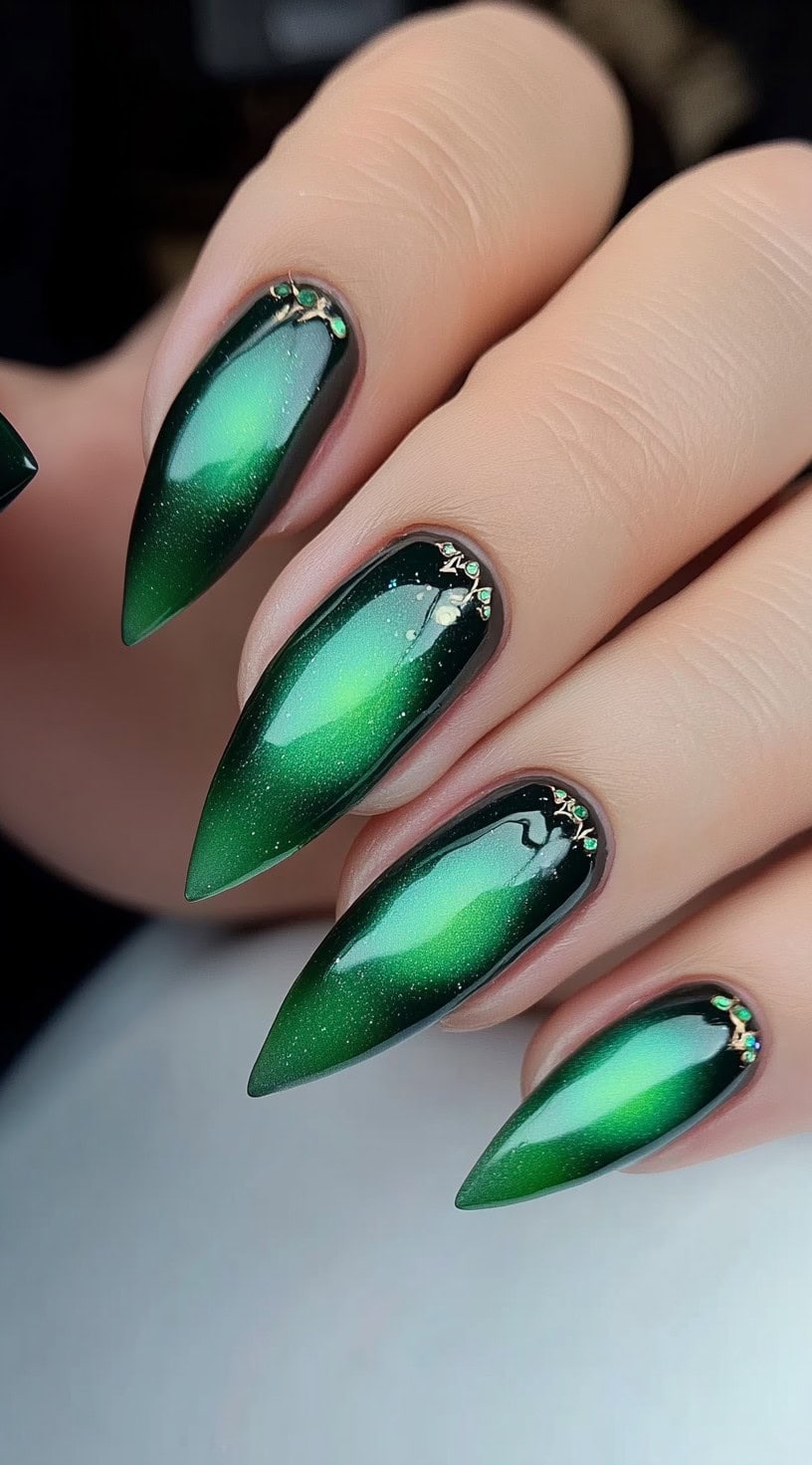 Dramatic stiletto nails featuring a mesmerizing green cat-eye effect with delicate crystal embellishments.
