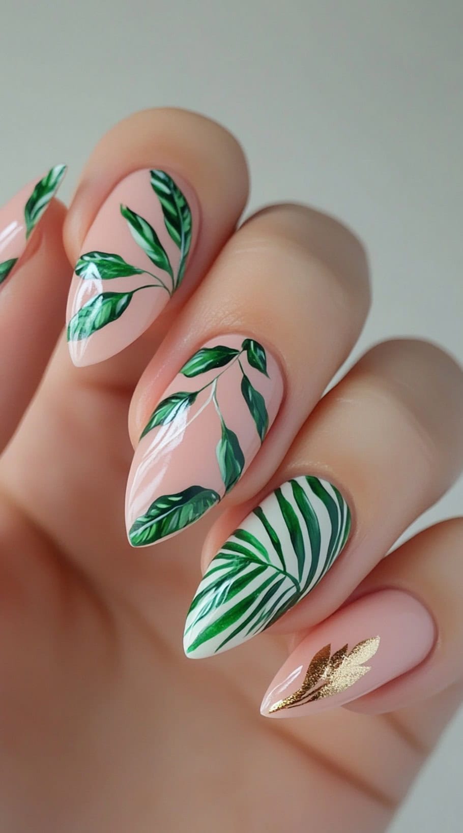 Almond-shaped nails with natural green leaf patterns and a subtle gold accent.