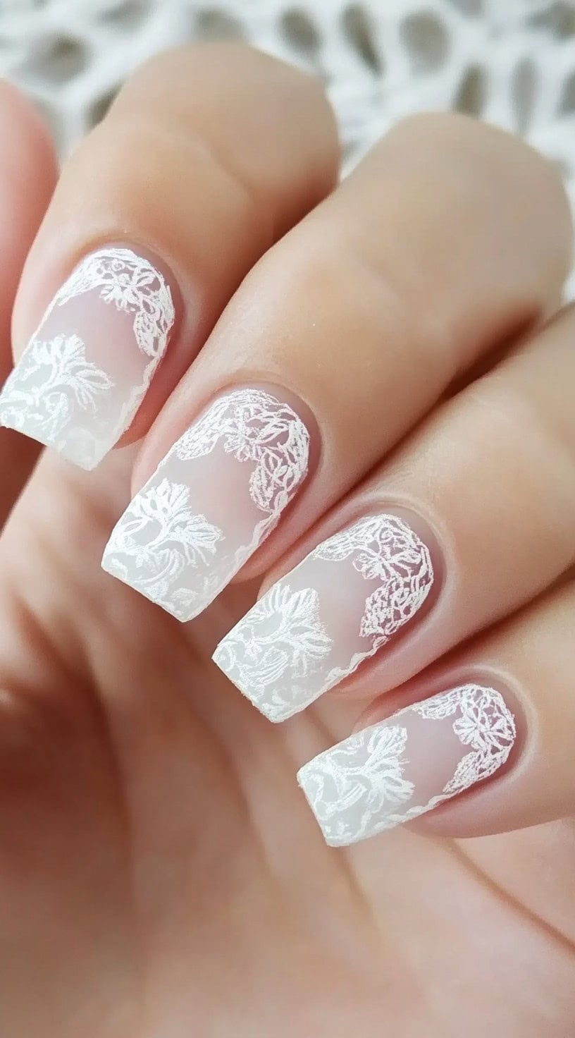 Square-shaped nails with a sheer base and intricate white lace-like detailing.