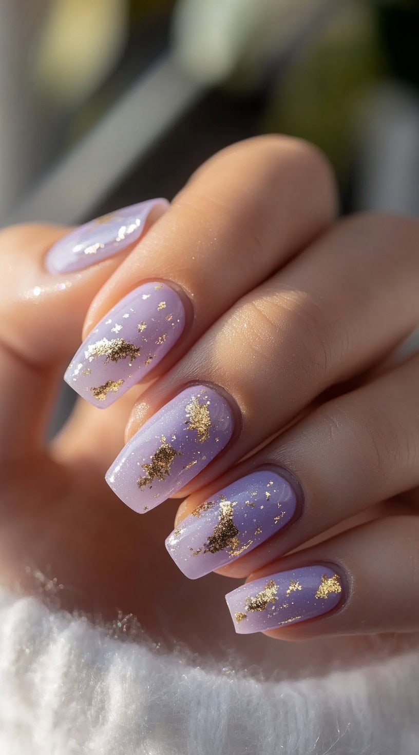 A close-up of square lavender gel nails with delicate gold foil accents, creating a dreamy and elegant wedding manicure.