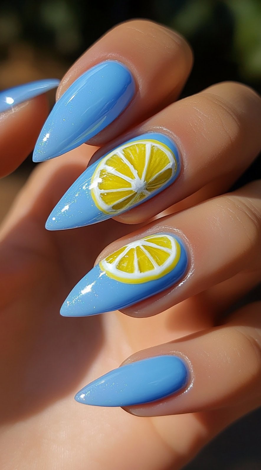 Almond-shaped nails with glossy light blue polish and bright yellow lemon slice accents.