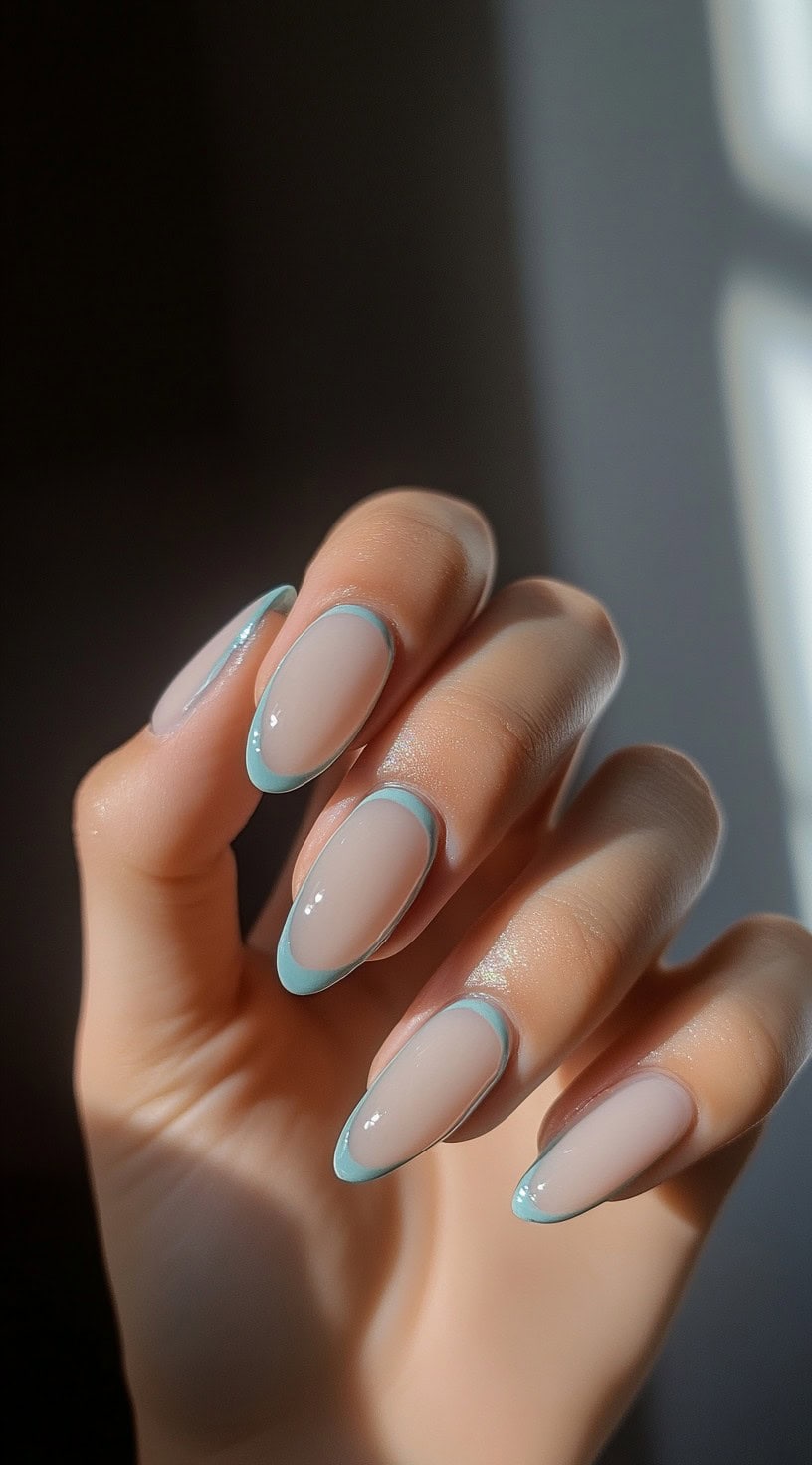 Neutral almond nails outlined with light blue French tips.