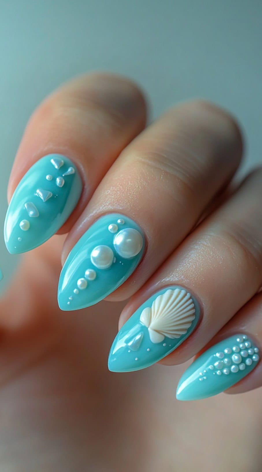 Light blue almond nails with raised pearl and shell accents.