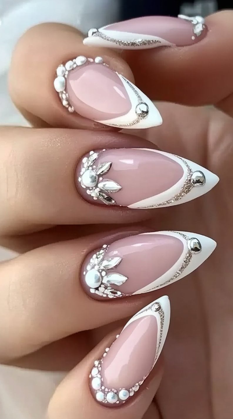 Dramatic almond-shaped French nails with 3D rhinestones and metallic accents.