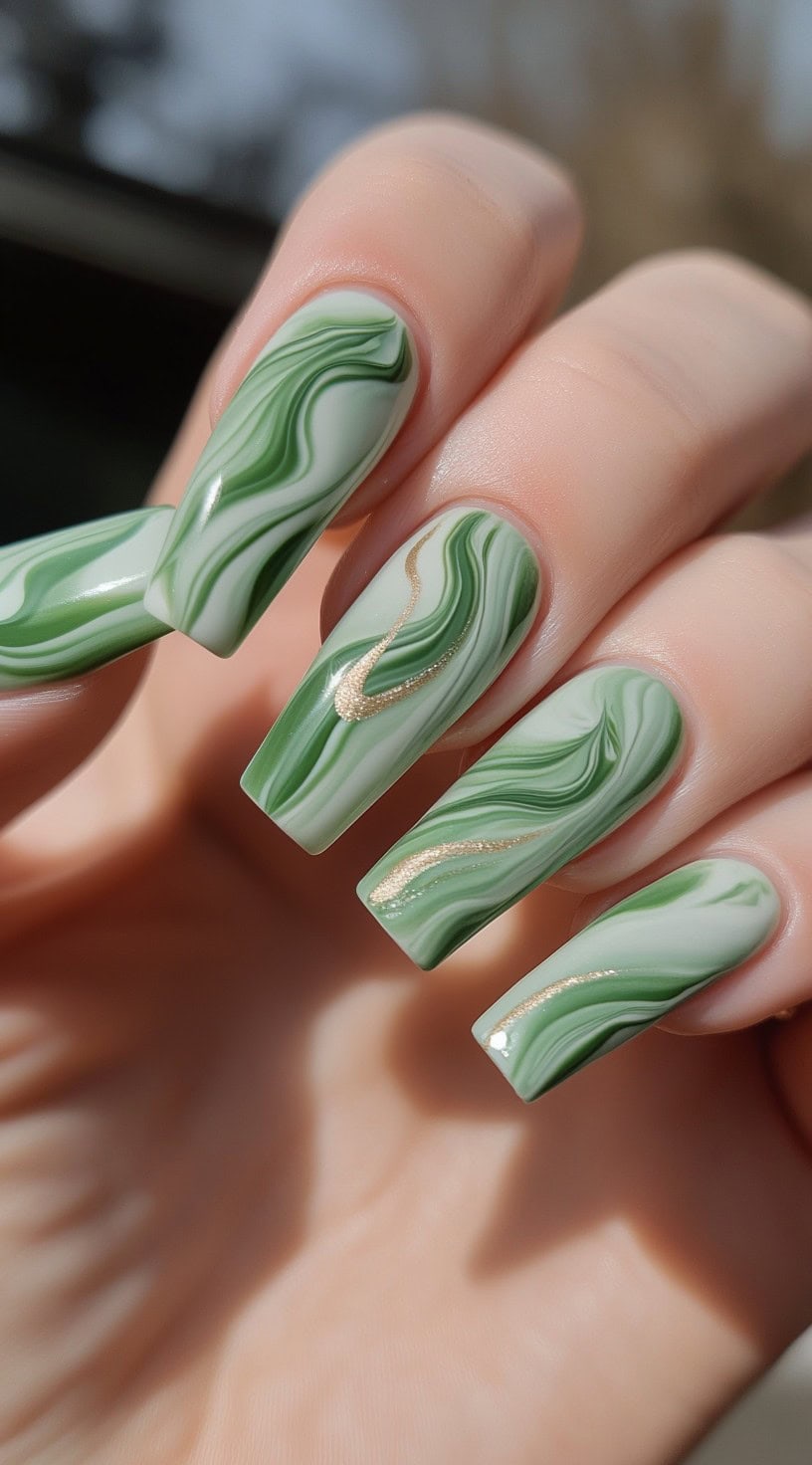 Coffin-shaped nails featuring a green and white marble swirl design with metallic gold accents.