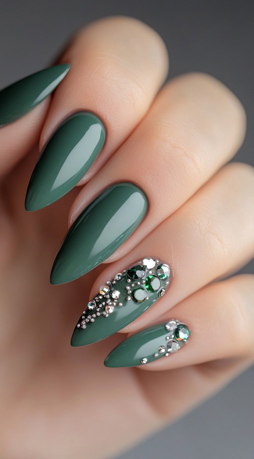 Stiletto nails in a glossy matcha green with two accent nails embellished with green and silver rhinestones.