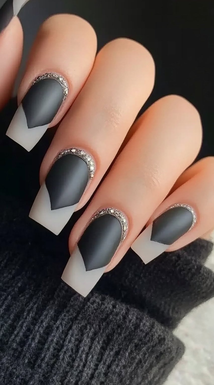 A set of square-shaped nails featuring a matte black design with a sharp French tip effect, framed by a line of sparkling crystals.