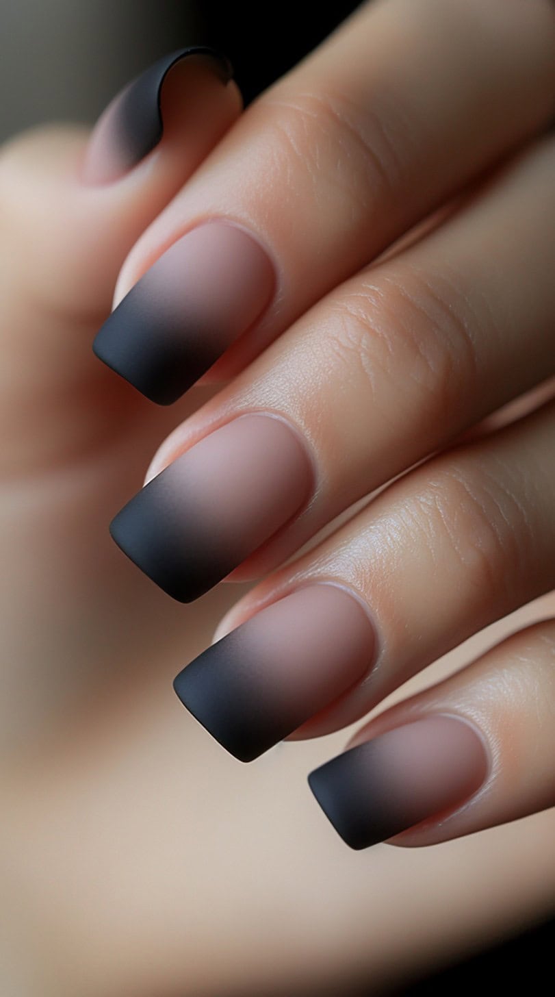 Close-up of square-shaped nails featuring a matte pink base that gradually darkens into a deep matte black ombre at the tips.