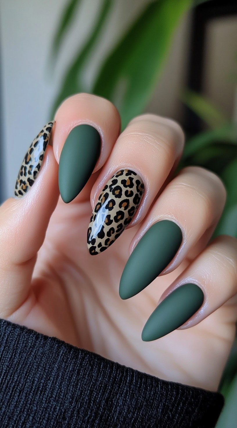 Almond-shaped nails in matte matcha green with two glossy leopard-print accent nails on a beige background.