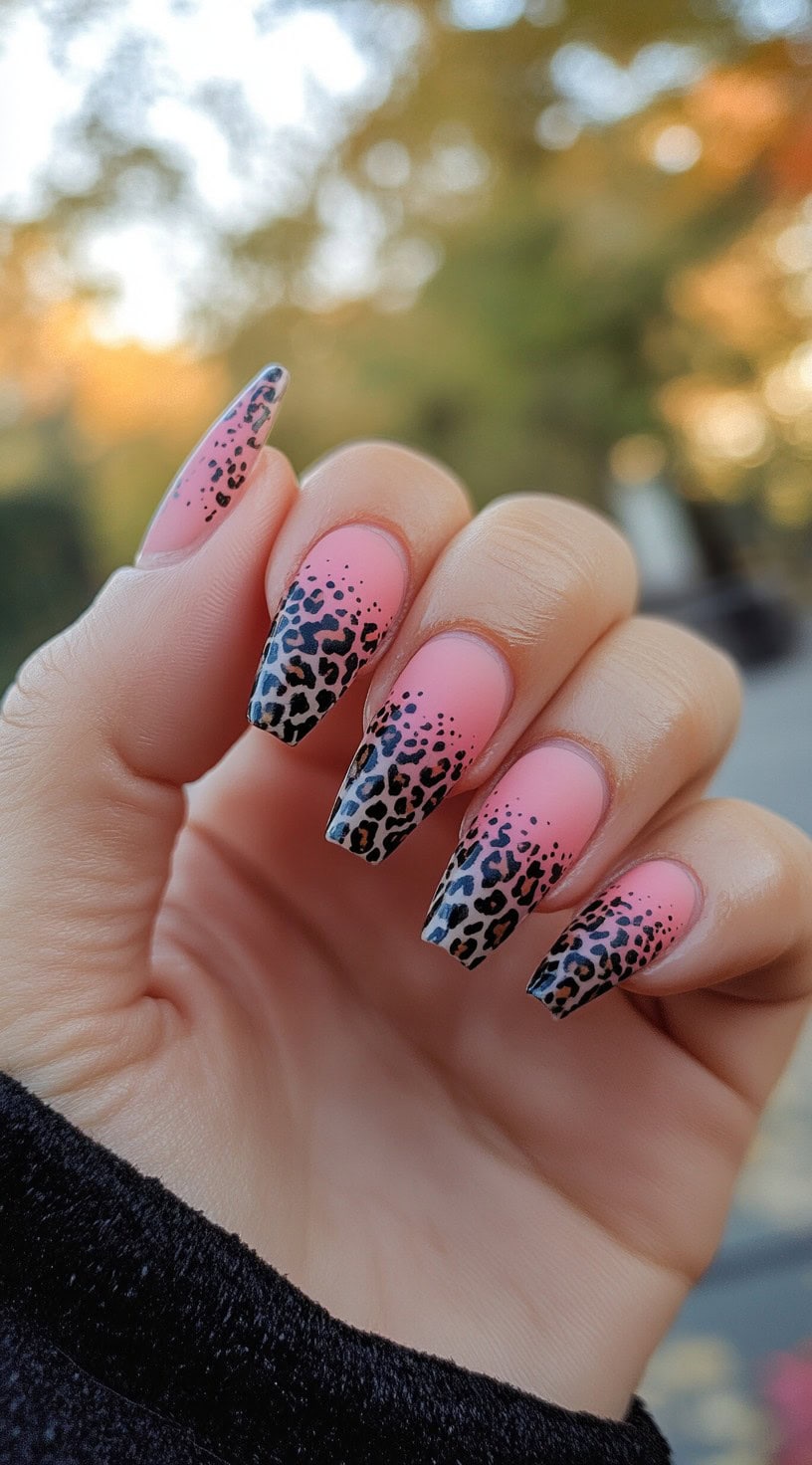 Long coffin nails with a matte pink to black ombre background covered in black and brown leopard spots.