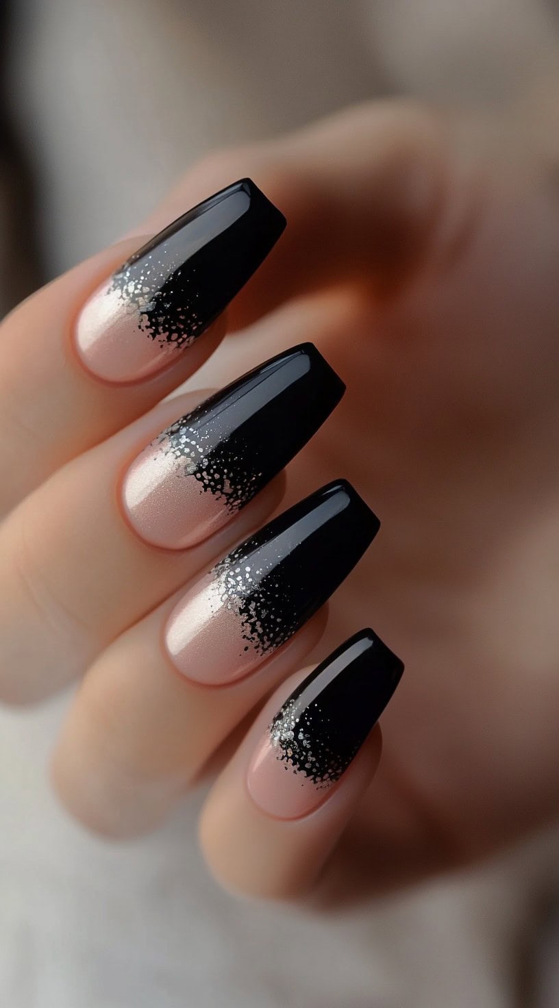 Coffin-shaped nails with a soft blush base fading into opaque black tips, dusted with micro-glitter at the transition point.