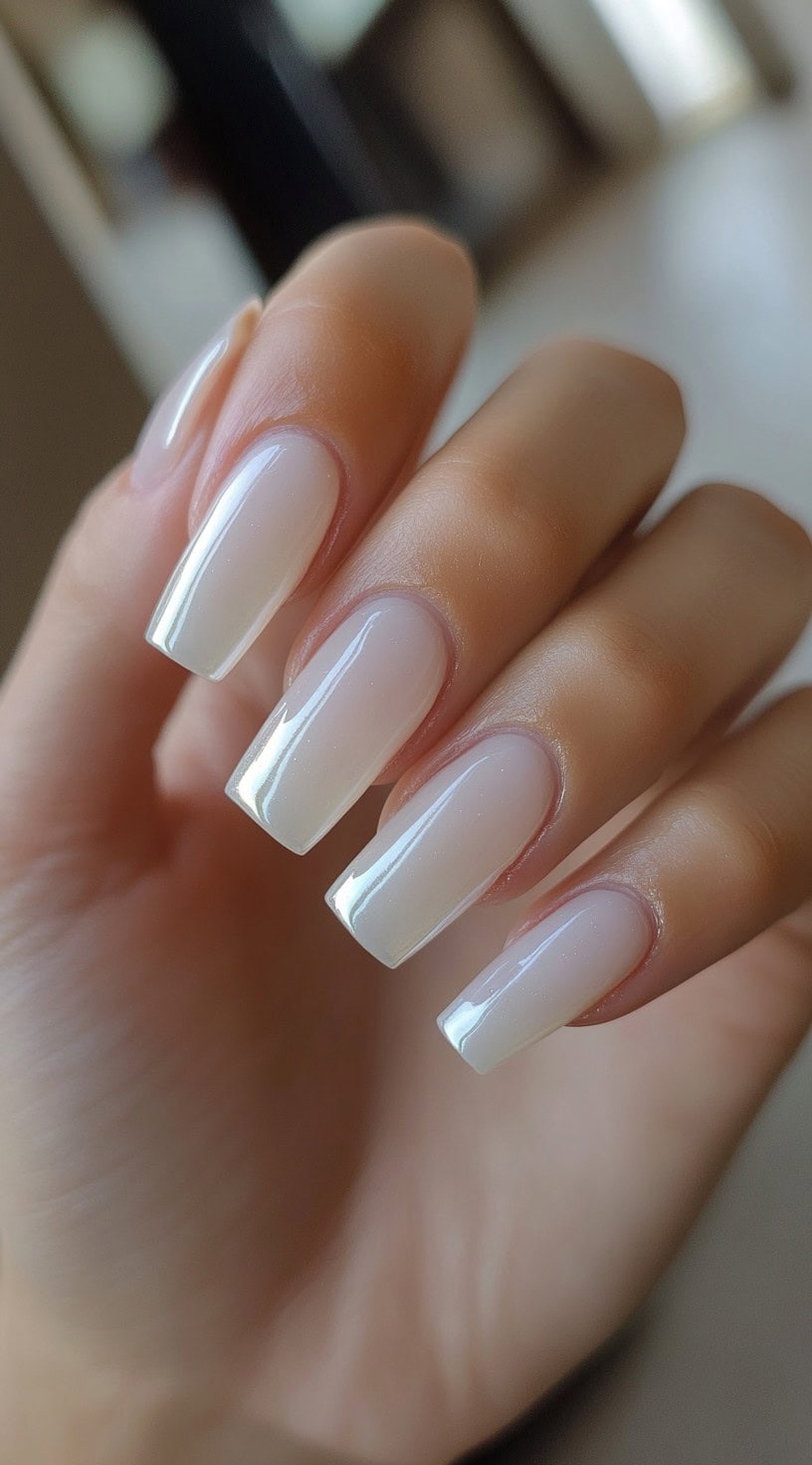 Coffin-shaped nails with a glossy milky white polish, creating a soft, ethereal appearance.