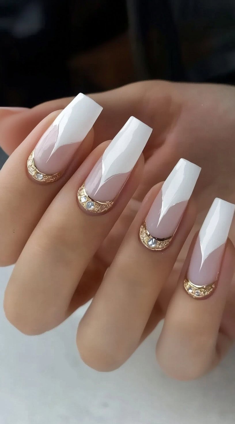 Long coffin-shaped French nails with sharp, geometric white tips and gold detailing at the cuticles.