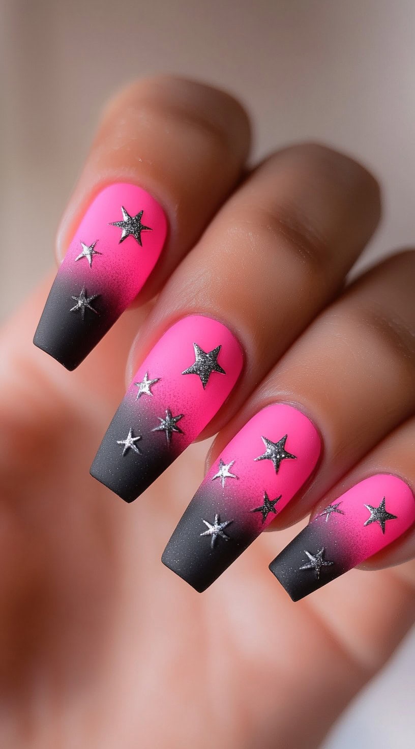 Coffin-shaped nails with a neon pink to black ombre fade, decorated with small silver star decals.