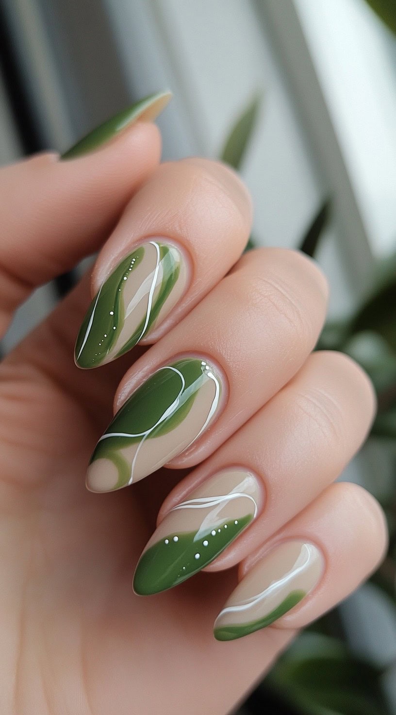 Almond-shaped nails featuring abstract olive green swirls on a neutral base with white and dot accents.