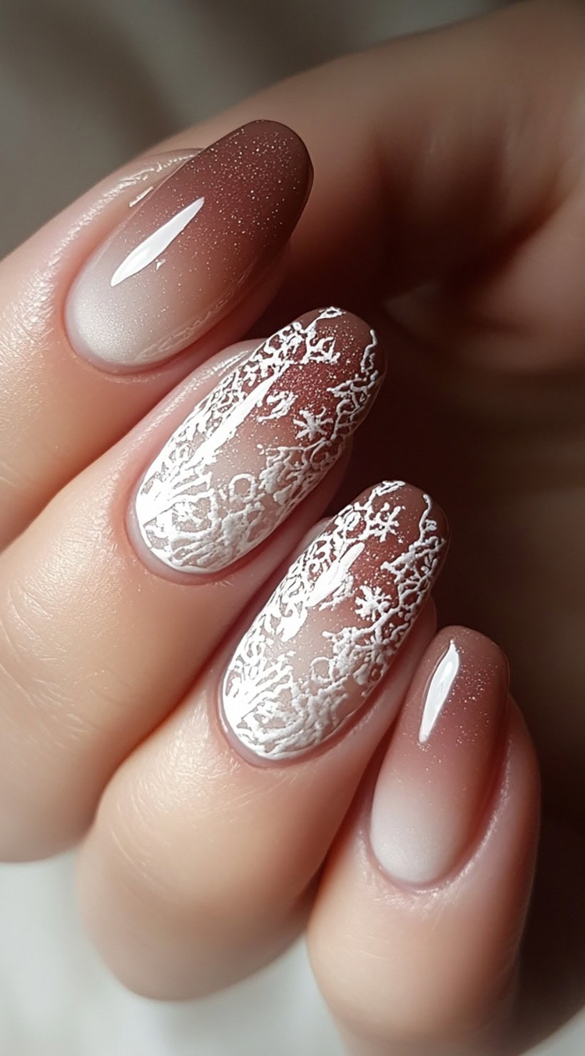 Oval nails showcase a soft pink and brown ombre base with intricate white lace patterns on two accent nails.
