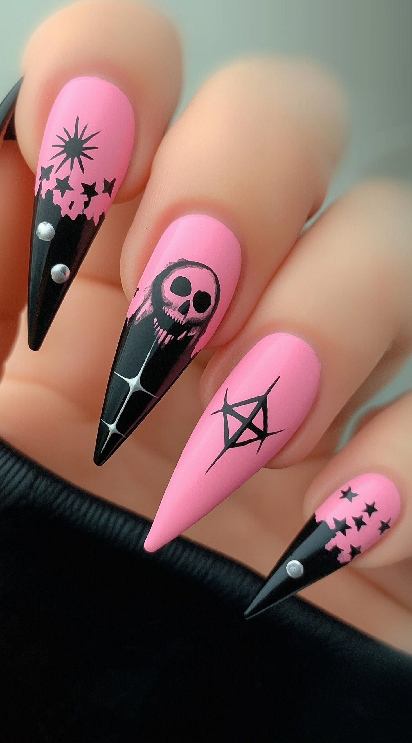 Stiletto nails with pink and black contrast, decorated with skulls, stars, spikes, and anarchy symbols.