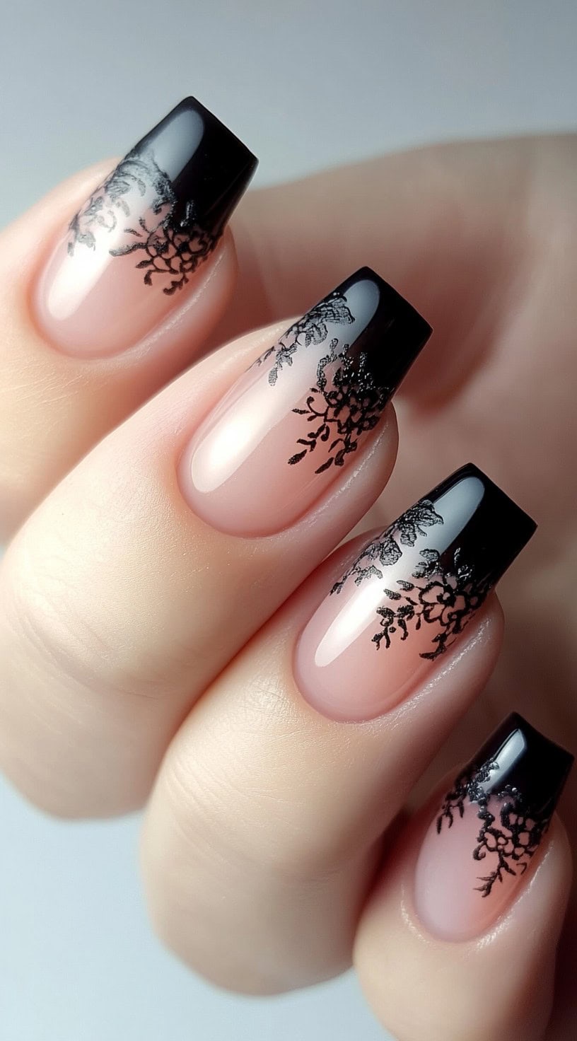 Square nails with a soft pink to black gradient and delicate black lace-like floral tips.