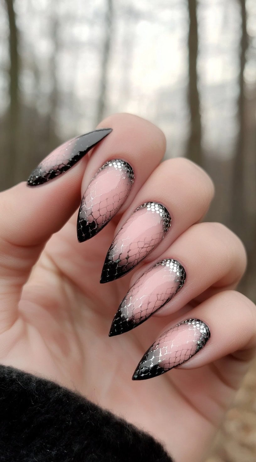 Hand with long almond-shaped nails showcasing a pink-to-black ombre topped with shiny silver hex patterns resembling snake skin and glitter along the cuticles.
